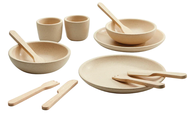 Toddler pretending to pour and feed with toy cups, bowls, and spoons, an action-word language toy for 18 months and up